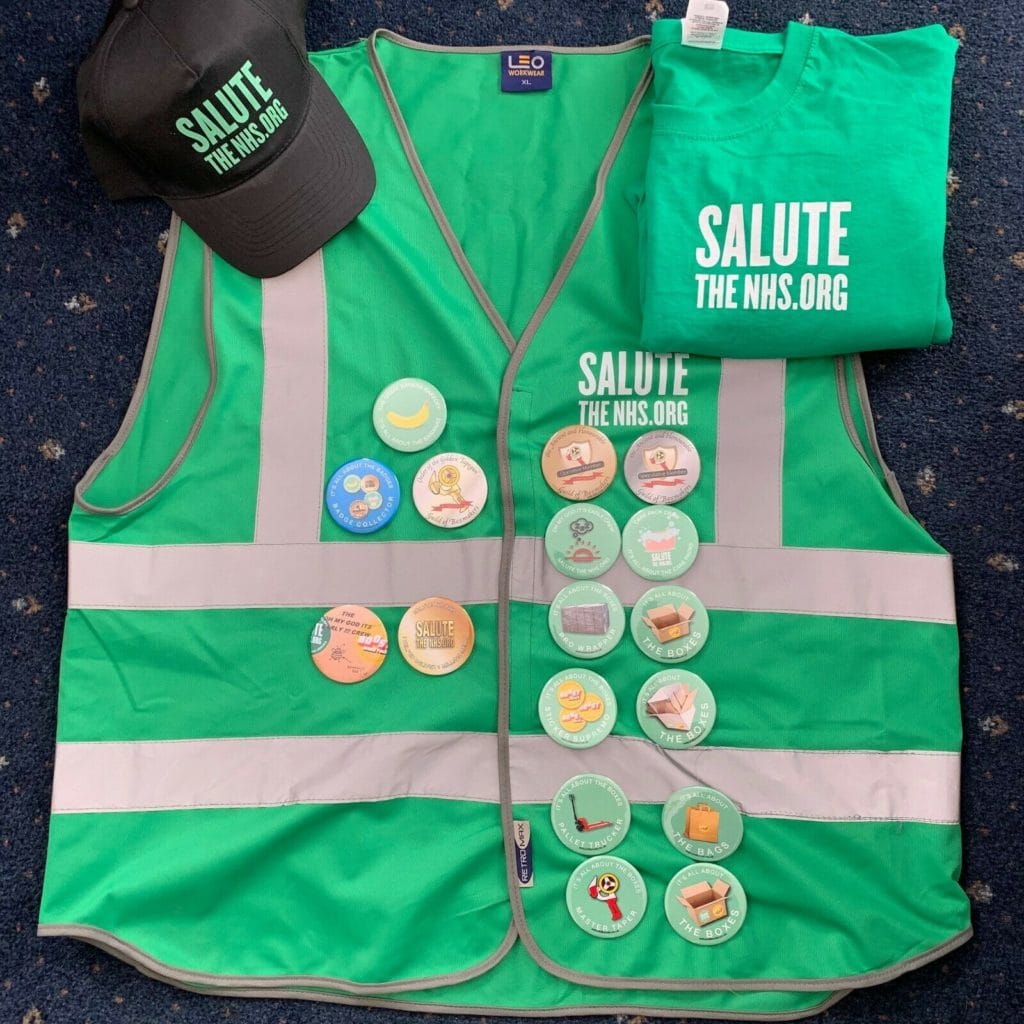 Image of 'Salute the NHS' memorabilia, including a cap, a t-shirt, and badges with 'Salute the NHS' and 'I helped to deliver one million meals' slogans on/
