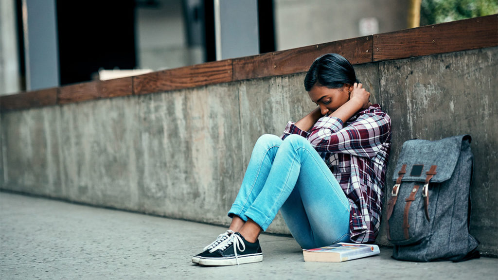 Young girl sat on the floor outside looking stressed